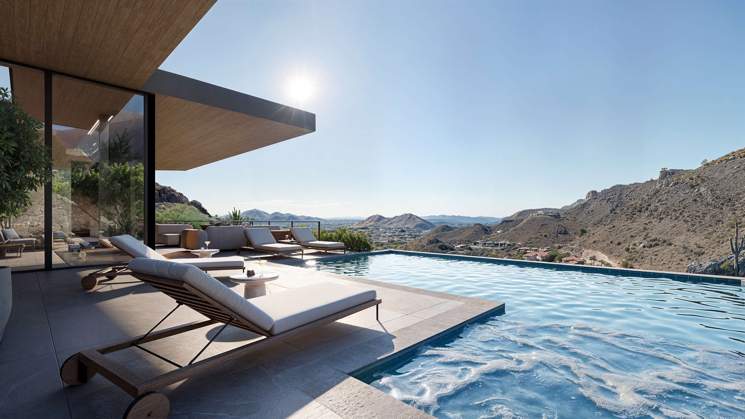 Pool terrace at midday — spa spilling into the infinity-edge pool beneath the wood-clad cantilevered soffit, teak chaise lounges and a low lounge, the valley and mountains beyond
