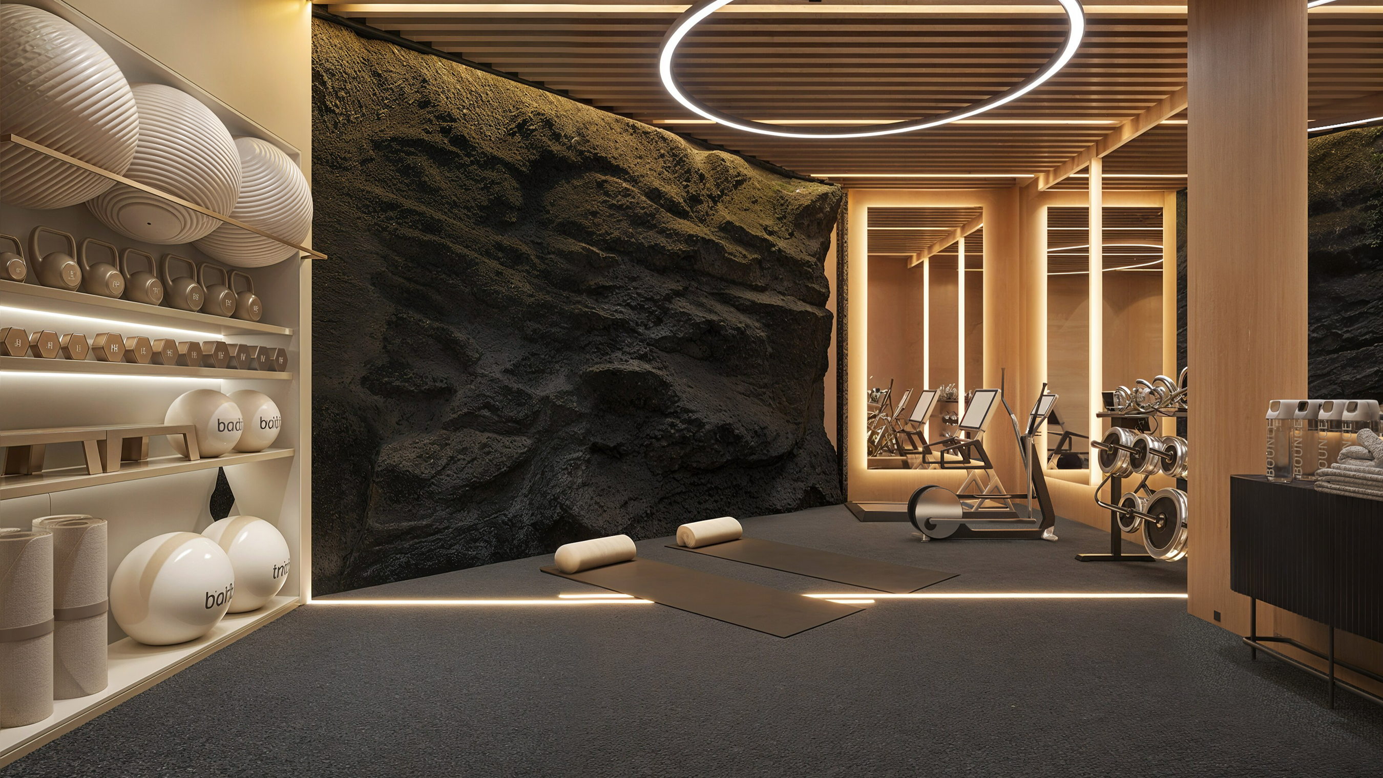 Home gym opened against an exposed black lava-rock wall, with kettlebells, dumbbells and a mirrored treadmill alcove